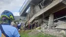 Tim penyelamat mencoba menarik seorang warga yang terperangkap dari bawah reruntuhan bangunan setelah gempa kuat melanda La Trinidad, Provinsi Benguet, Filipina, 27 Juli 2022. Guncangan gempa menyebabkan banyak tembok rumah dan bangunan yang retak, termasuk beberapa runtuh. (Bureau of Fire Protection via AP)