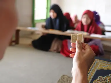 Kyai Tubagus Muhammad Tamyiz mengaji dengan  Al Quran mini bertinta emas saat mengajar  para santri  memaknai Kitab Kuning' di Pondok Pesantren Almiizan, Kabupaten Bogor, Jawa Barat, Zenin, (20/5/2019). Al Quran mini ini berukuran 10 mm x 10 mm. (merdeka.com/Arie Basuki)