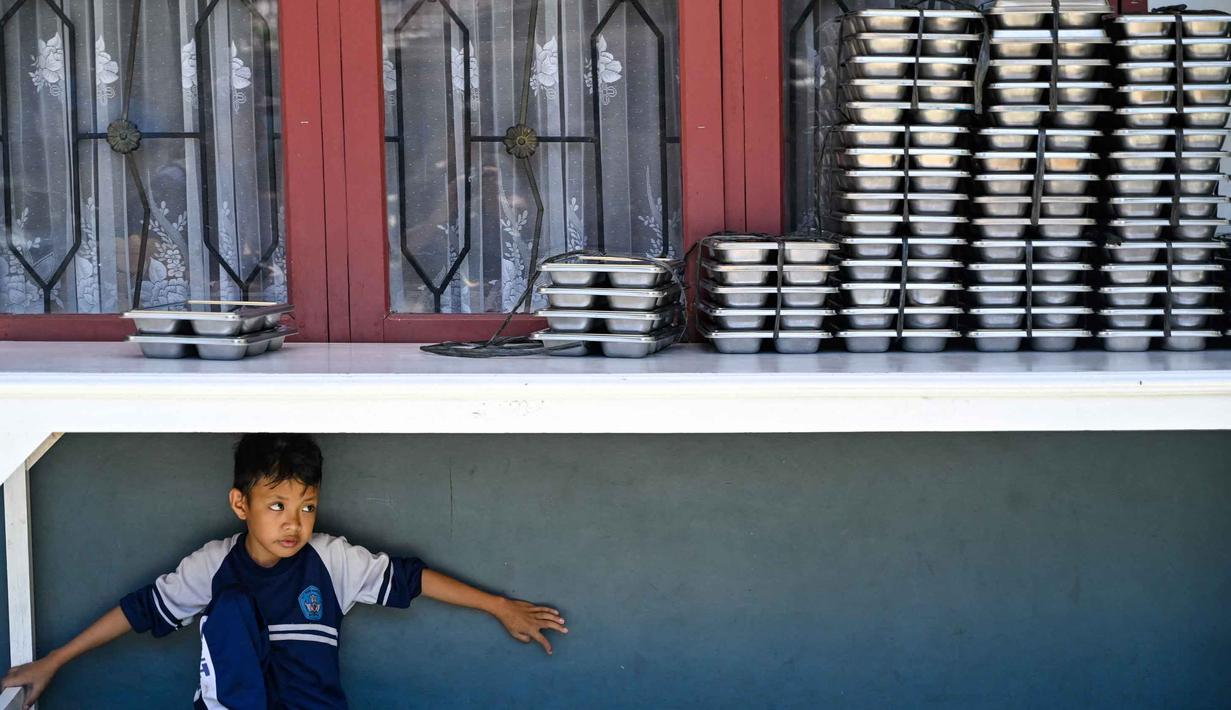 Seorang siswa menunggu makanan yang disediakan oleh program Makan Bergizi Gratis (MBG) di sebuah sekolah dasar di Banda Aceh pada Kamis 30 Oktober 2025. Selain siswa, program ini juga ditujukan untuk ibu hamil, ibu menyusui, dan balita. (CHAIDEER MAHYUDDIN/AFP)