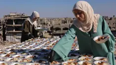 Kakak beradik Palestina, Lina Zeid (kanan) dan Aya Zeid, menyiapkan piring makanan di atap rumah mereka untuk dibagikan kepada anak-anak pengungsi sebagai kegiatan amal di daerah Al-Tuam, sebelah barat Jabalia, Jalur Gaza Utara pada Rabu 6 Mei 2026. (Omar AL-QATTAA/AFP)