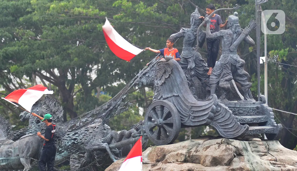Massa aksi demo tolak omnibus law UU Cipta Kerja naik ke atas patung arjuna wiwaha mengibarkan bendera merah putih di Jalan Medan Merdeka Barat, Jakarta Pusat, Selasa (20/10/2020). (merdeka.com/ Arie Basuki)