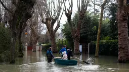 Seorang wanita menggunakan perahu membawa anak-anak di sebuah jalan banjir di Villennes sur Seine, sebelah barat Paris, (30/1). Meluapnya sungai Seine di Paris membuat kebun dan jalan terendam banjir. (AP Photo / Thibault Camus)