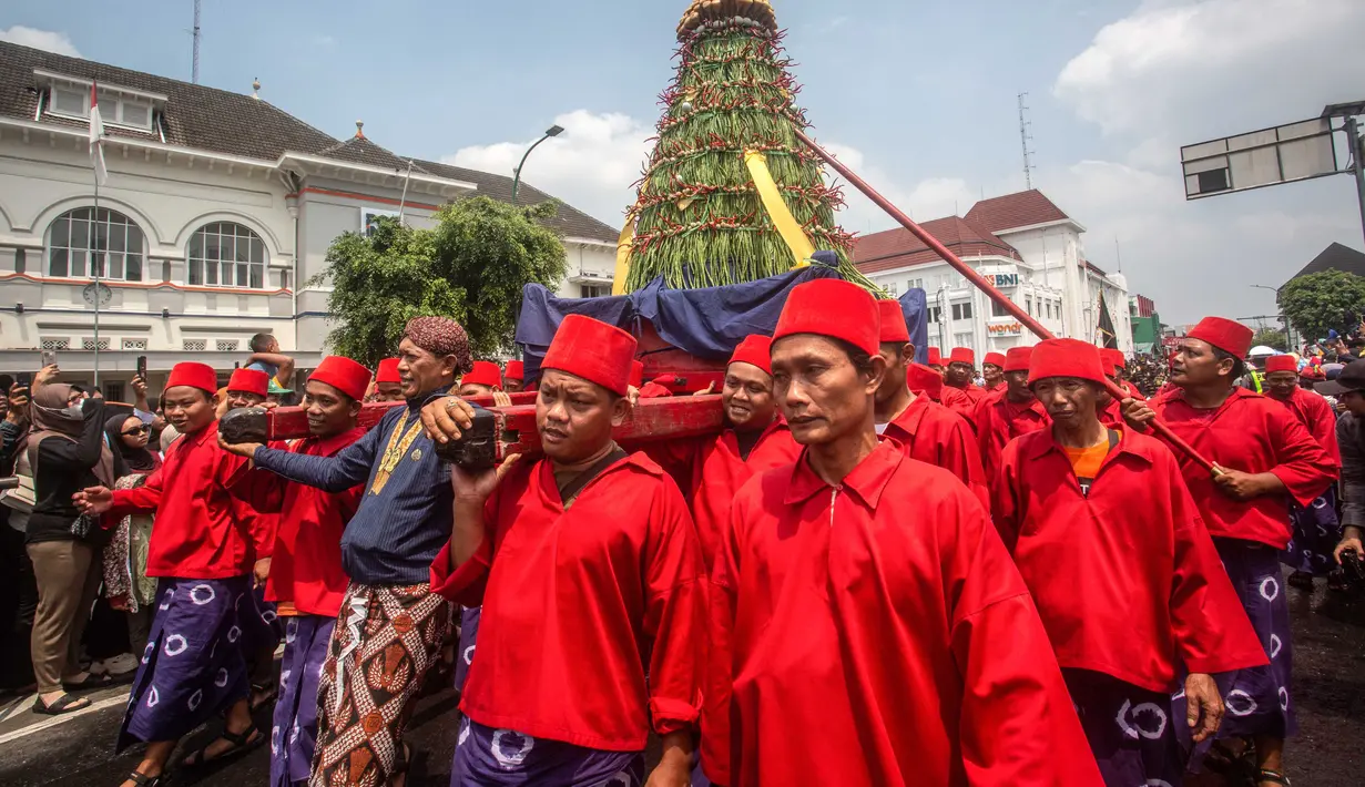 Para pengawal keraton yang dikenal secara lokal sebagai ‘abdi dalem’ membawa gunungan, sebuah persembahan berbentuk gunung dari hasil panen, selama upacara Grebeg, tradisi suci Keraton Yogyakarta pada 5 September 2025. (DEVI RAHMAN/AFP)