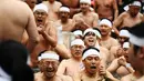 Orang-orang percaya Shinto dari Kuil Teppozu Inari mandi dengan air dingin untuk menyucikan jiwa dan tubuh mereka selama ritual Tahun Baru di Tokyo, Minggu (12/1/2020). Sekitar 100 orang percaya Shinto ambil bagian dalam ritual tahunan tersebut. (AFP/Charly Triballeau)