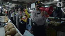 Petugas Polres Jakarta Timur melakukan sosialisasi dan membagikan masker di Pasar Palmeriam, Matraman, Selasa (9/2/2021). Kegiatan itu dilakukan sebagai upaya meningkatkan kesadaran masyarakat akan pentingnya penerapan protokol kesehatan untuk menekan penyebaran Covid-19. (merdeka.com/Imam Buhori)