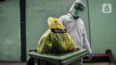 Petugas mengenakan APD saat membawa kantong berisi limbah Covid-19 ke Tempat Penyimpanan Sementara Limbah B3 di Laboratorium Kesehatan Daerah (Labkesda) DKI Jakarta, Selasa (4/8/2020). Pembuangan limbah Covid-19 dilakukan dengan proses ketat sesuai protokol kesehatan. (merdeka.com/Iqbal Nugroho)
