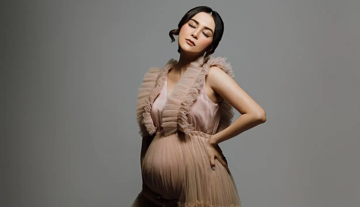 Setelah sebelumnya berpose sambil duduk, setelahnya Vicy Melanie berpose berdiri sembari menutup mata. Pencahayaan lampu yang gelap, membuat hasil foto Vicy Melanie ini estetik. Makin cantik ketika hamil, tak sedikit netizen yang memuji istri Kevin Aprilio ini. Bahkan Addie MS pun turut membubuhkan komentar pujian dan mendoakan kesehatan untuk menantu tercintanya ini. (Liputan6.com/IG/@vicymelanie)