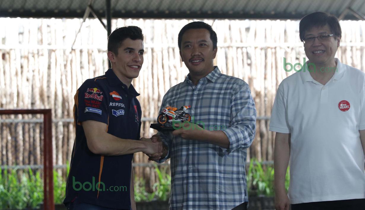 Marc Marquez memberikan cinderamata berupa replika motor balap kepada  Menpora, Imam Nahrowi didampingi CEO AHM, Yohanes Loman (kanan) di Lapangan Futsal Kuningan Village, Jakarta, Sabtu (13/2/2016). (Bola.com/Nicklas Hanoatubun)