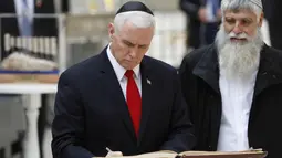 Wakil Presiden AS Mike Pence (kiri) menandatangani buku tamu saat berkunjung ke Tembok Barat Yerusalem (23/1). Mike Pence berjanji untuk memindahkan kedutaan ke kota yang disengketakan tersebut pada akhir tahun 2019. (AFP Photo/Thomas Coex)