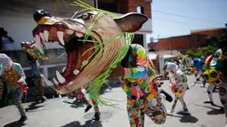 Seorang pria mengenakan kostum dan topeng binatang saat mengikuti perayaan tradisional di Naiguata, Venezuela (31/5). Perayaan tradisional Corpus Christi di kota pesisir Venezuela ini bertujuan untuk memuliakan Tuhan. (AP/Arian Cubillos)