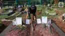 Sardi, pengurus makam membersihkan makam Vanessa Angel dan Bibi Ardiansyah di TPU Taman Makam Islam Malaka Blok D, Pesanggrahan, Jakarta, Senin (7/02/2022). Makam yang berada di atas tanah wakaf dirapikan dengan semen oleh pengurus makam agar tanah tidak amblas. (Liputan6.com/Fery Pradolo)