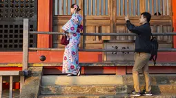 Seorang pria mengambil foto temannya yang mengenakan kimono di kuil Buddha Kiyomizu-dera di Kyoto, Jepang (31/10/2019). Kuil ini adalah situs Warisan Dunia UNESCO dan salah satu tempat wisata paling terkenal di Kyoto. (AP Photo / Aaron Favila)