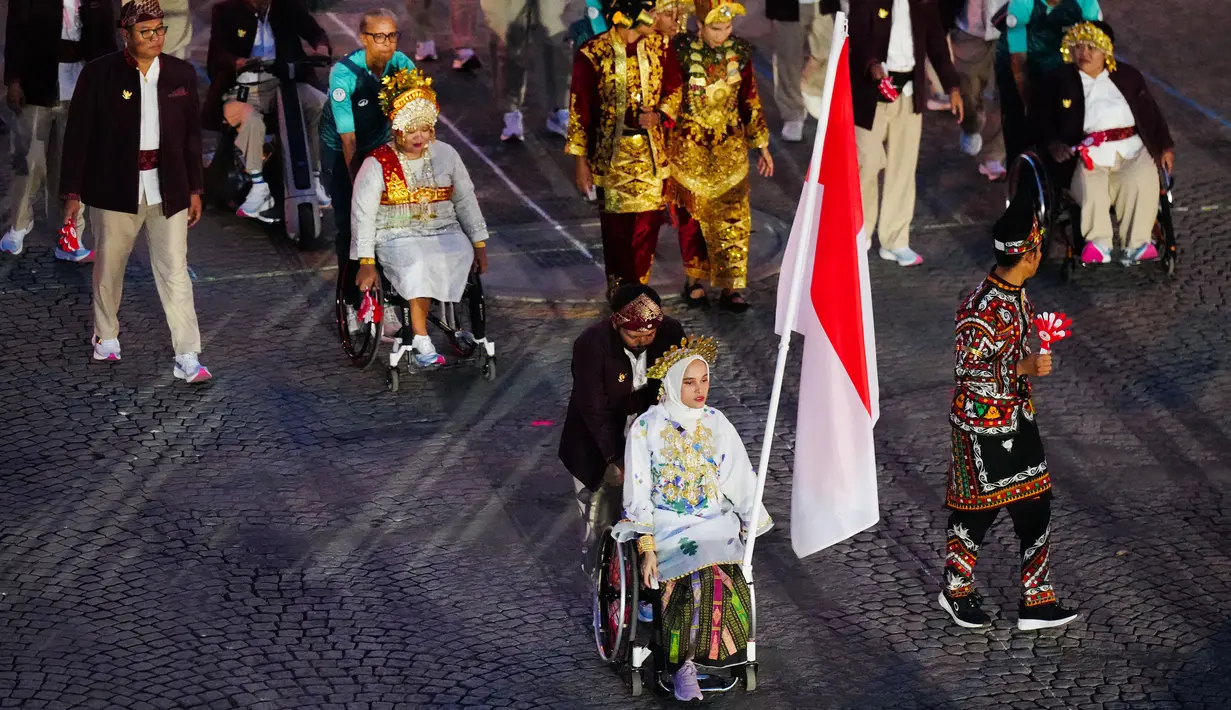 Atlet para-tenis meja Indonesia, Leli Marlina (kiri) dan atlet para-balap sepeda Indonesia, Muhammad Fadli Imammuddin terpilih sebagai pembawa bendera saat upacara pembukaan Pralimpiade Paris 2024 yang berlangsung di jalan raya ikonis Kota Paris, Place de la Concorde, Paris, Prancis, Rabu (28/08/2024) waktu setempat. (AFP/Dimitar Dilkoff)