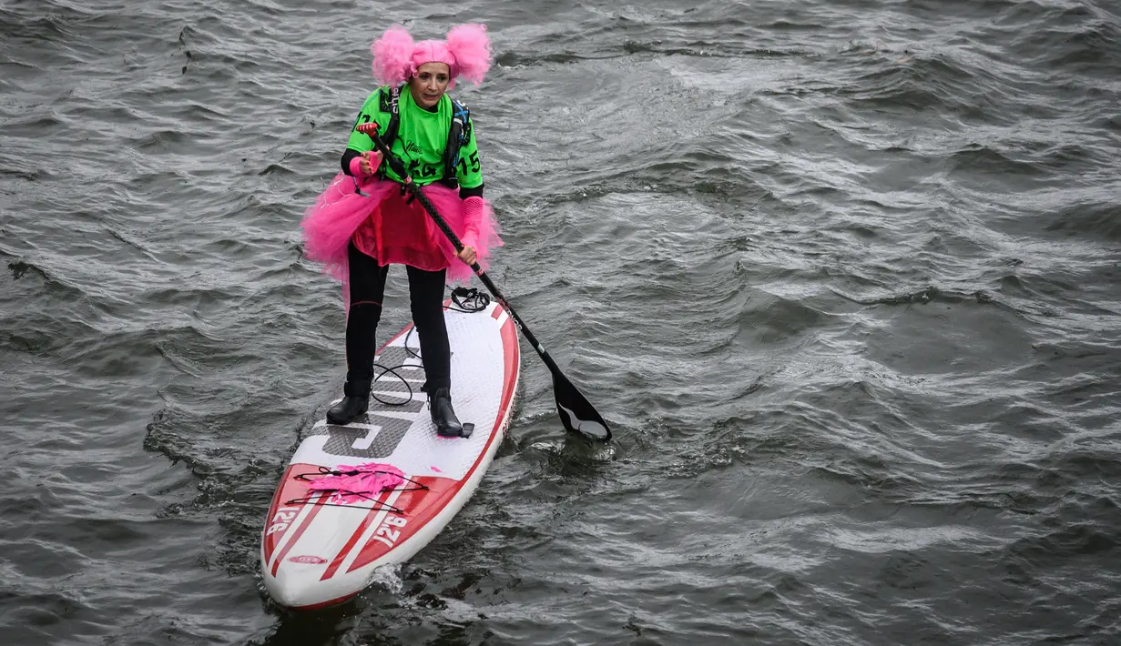 Seorang peserta mengenakan saat lomba dayung sambil berdiri pada edisi ke-10 Nautic Paddle Race di Sungai Seine, Paris, Minggu (8/12/2019). Sekitar 1000 pesaing ikut serta dalam lomba sejauh 11 kilometer menyeberangi sungai Seine dengan pemandangan kota Paris. (Photo by Olivier MORIN / AFP)