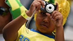 Bergaya bak fotografer profesional, seorang bocah Brasil mengabadikan laga Iran kontra Nigeria di babak penyisihan Piala Dunia 2014 Grup F di Baixada Arena, 16/6/2014). (AFP PHOTO/Jewel Samad)