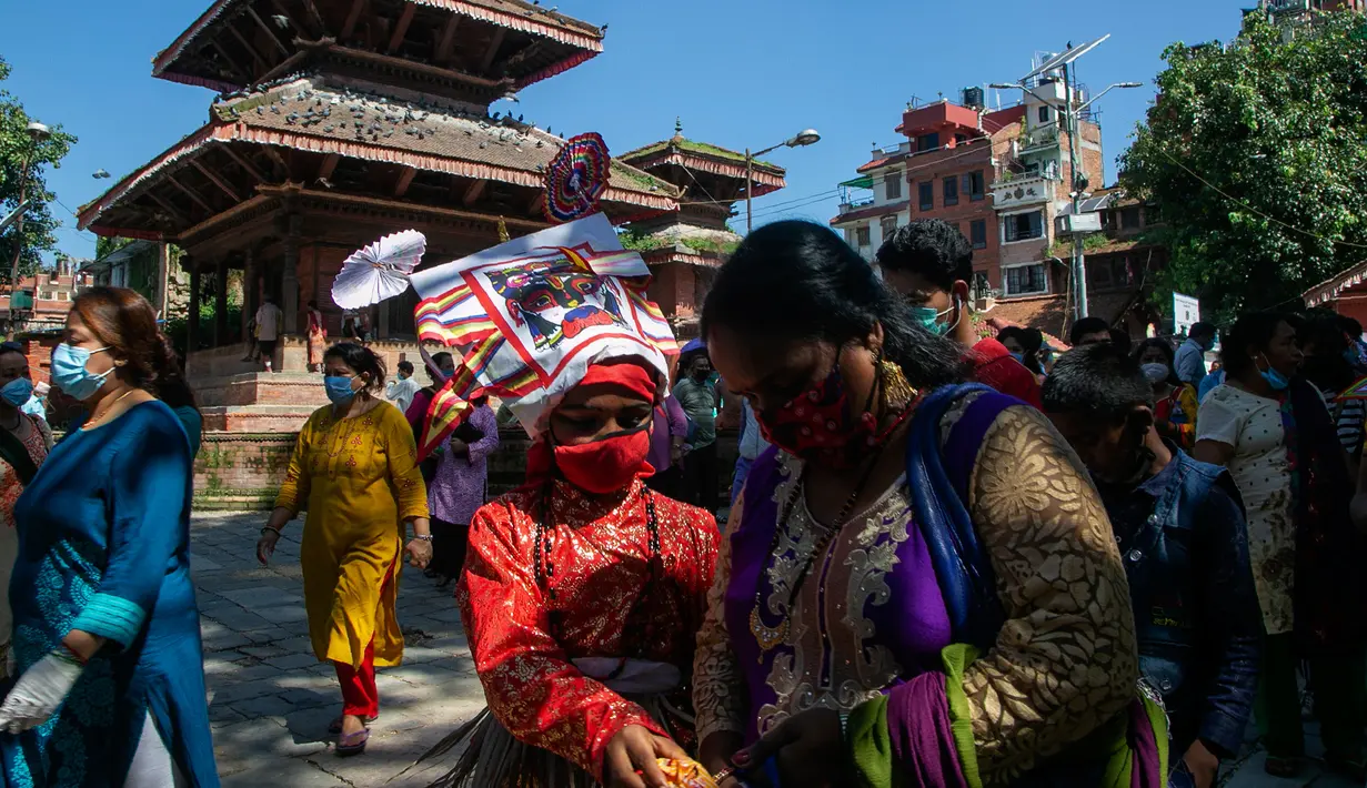 Anggota komunitas Newar mengenakan kostum dan masker saat berpartisipasi dalam prosesi 'Gai Jatra', atau festival sapi, di Kathmandu, Nepal, Selasa (4/8/2020). Festival ini untuk meminta keselamatan dan kedamaian bagi orang yang mereka cintai yang telah meninggal. (AP Photo/Niranjan Shrestha)