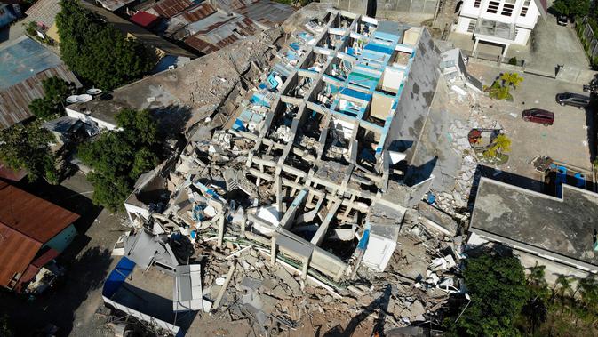 Petugas membersihkan puing-puing dari hotel Roa Roa yang runtuh di Palu, Sulawesi Tengah, Senin (1/10). Jumlah korban tewas akibat gempa dan tsunami yang melanda Palu dan Donggala diperkirakan akan meningkat. (JEWEL SAMAD/AFP)