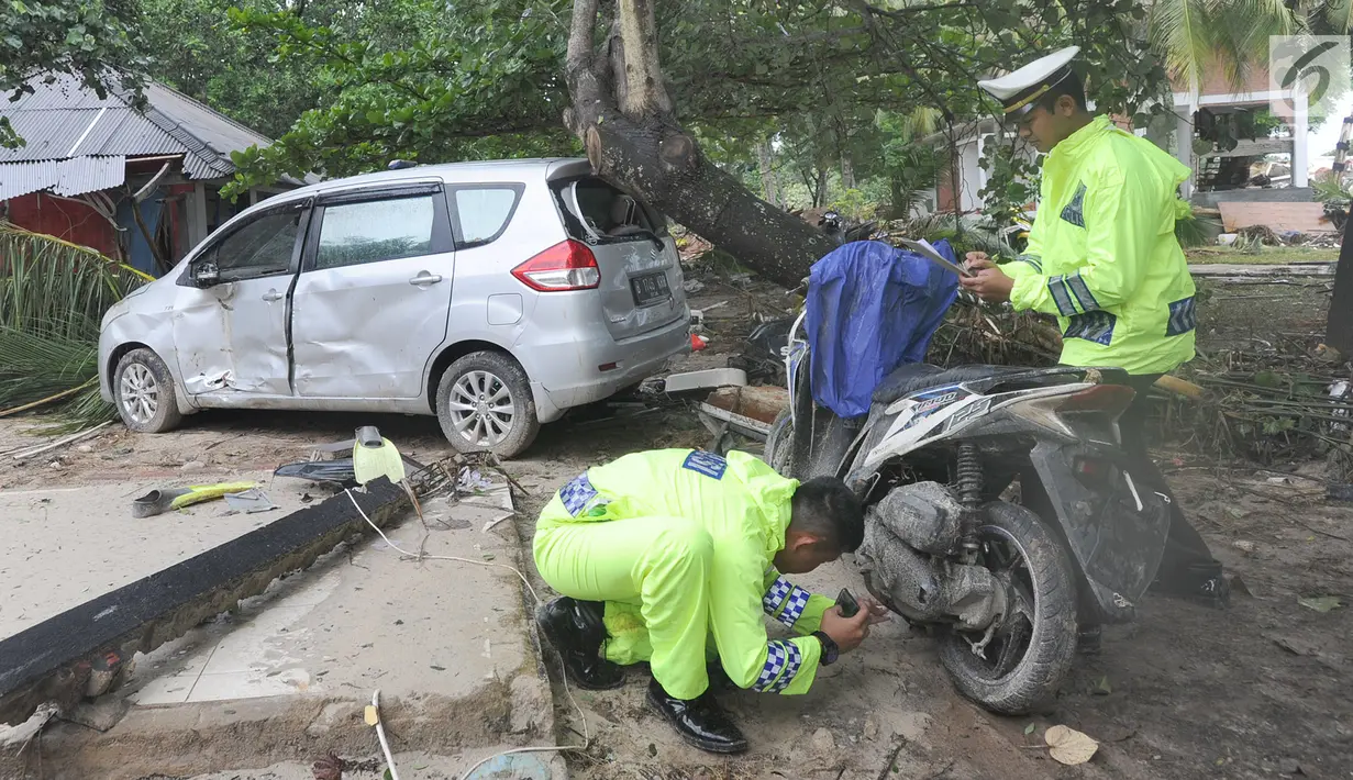 Petugas polisi lalu lintas dari Polres pandeglang melakukan identifikasi kendaraan motor  yang rusak akibat terjangan tsunami di Tanjung Lesung Beach Club, Pandeglang, Banten, selasa (25/12). (Merdeka.com/Arie Basuki)