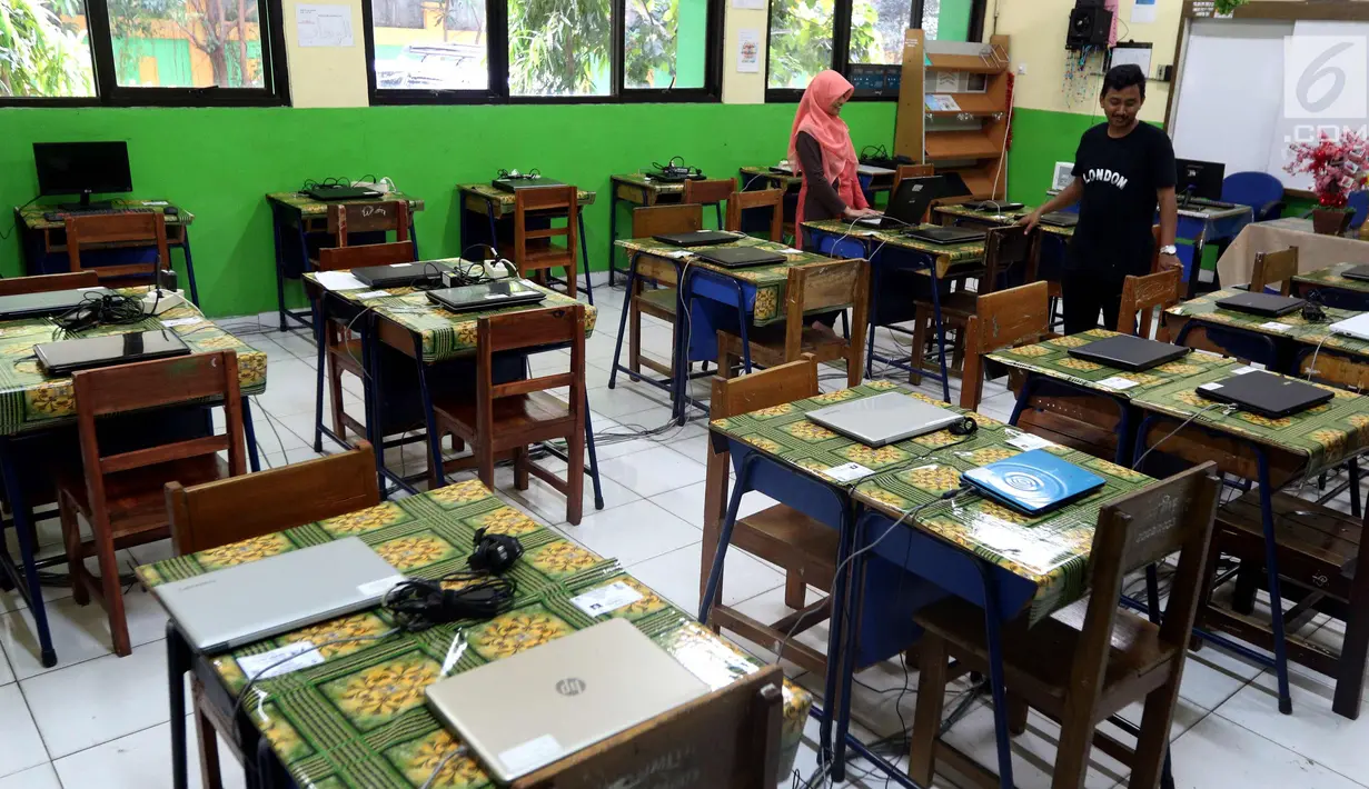 Petugas mengecek kesiapan laptop dan ruang untuk Ujian Nasional Berbasis Komputer di SMP N 34 Pademangan, Jakarta Utara, Minggu (22/4). UNBK SMP 2018 akan berlangsung mulai besok Senin (23/4). (Liputan6.com/Johan Tallo)