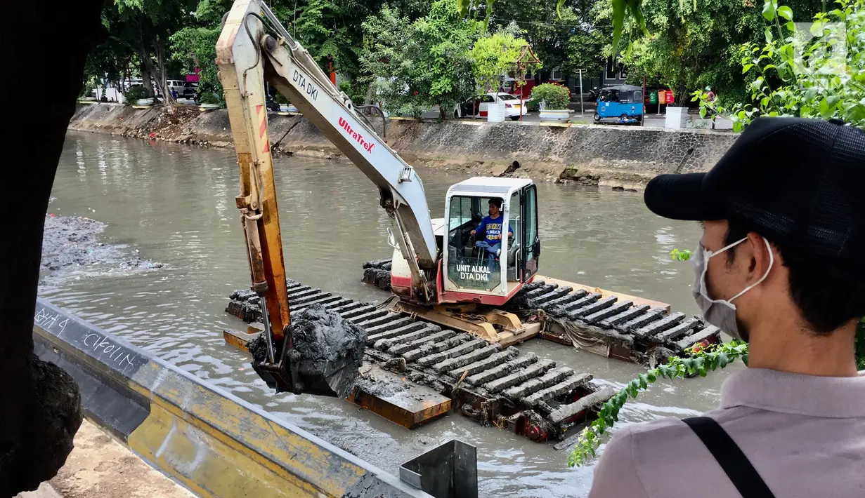 Pekerja menggunakan alat berat untuk mengeruk lumpur dan sampah yang mengendap di anak Sungai Ciliwung, Jakarta, Jumat (26/1). (Liputan6.com/Immanuel Antonius)