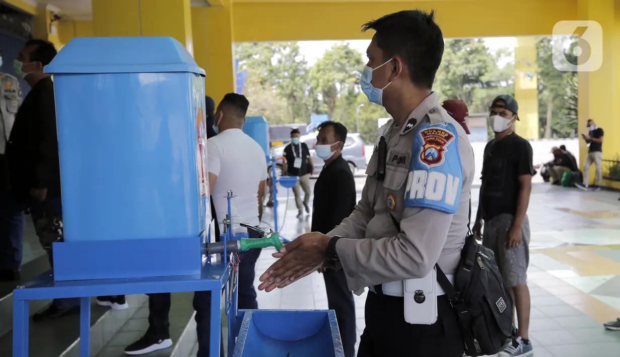 Seorang petugas kepolisian mencuci tangan sebelum melakukan swab antigen jelang pertandingan sepak bola Piala Menpora 2021 di Stadion Kanjuruhan, Malang, Jawa Timur, Senin (22/3/2021). (Bola.com/Arief Bagus)