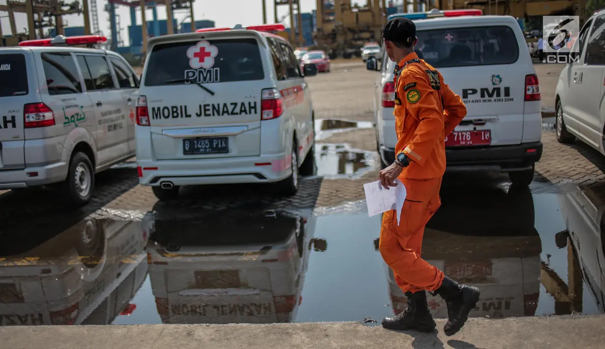 Petugas Basarnas melintas dekat mobil jenazah yang disiagakan di Posko Evakuasi Tanjung Priok, Jakarta, Senin (29/10). Posko itu menjadi tempat transit korban jatuhnya pesawat Lion Air JT610 di laut utara Karawang, Jawa Barat. (Liputan6.com/Faizal Fanani)