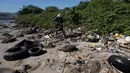 Seorang pria mengumpulkan sampah di pantai Pulau Pombeba, Teluk Guanabara, Rio de Janeiro, Brasil, Senin 17 Februari 2025. (Pablo PORCIUNCULA/AFP)