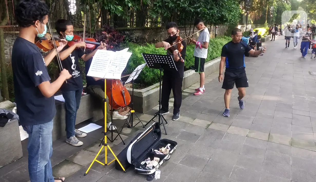 Musisi lokal Bogor memainkan musik klasik di pedestrian Kebun Raya, Jalan Pajajaran, Bogor, Jawa Barat, Minggu (14/6/2020). Untuk memenuhi kebutuhan hidup akibat sepinya job pertunjukan selama pandemi COVID-19, mereka memilih mengamen saat warga berolahraga. (merdeka.com/Arie Basuki)