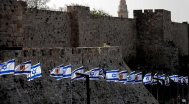 Bendera Israel berkibar di depan benteng-benteng di dekat Gerbang Jaffa di Kota Tua Yerusalem (20/3). Gerbang Jaffa adalah sebuah portal yang dibuat dari batu yang berada dalam deret tembok bersejarah Kota Lama Yerusalem. (AFP Photo/Thomas Coex)