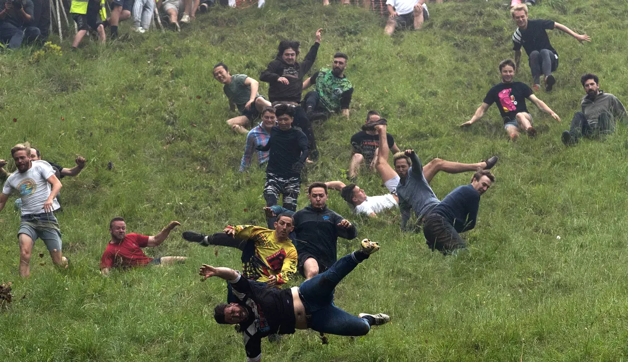 Sejumlah peserta berlari menuruni bukit curam untuk mengejar keju dalam kompetisi Cheese Rolling di Cooper's Hill di Brockworth, Gloucestershire, Inggris, Senin (28/5). Kompetisi ini diikuti ribuan peserta setiap tahunnya. (Aaron Chown/PA via AP)