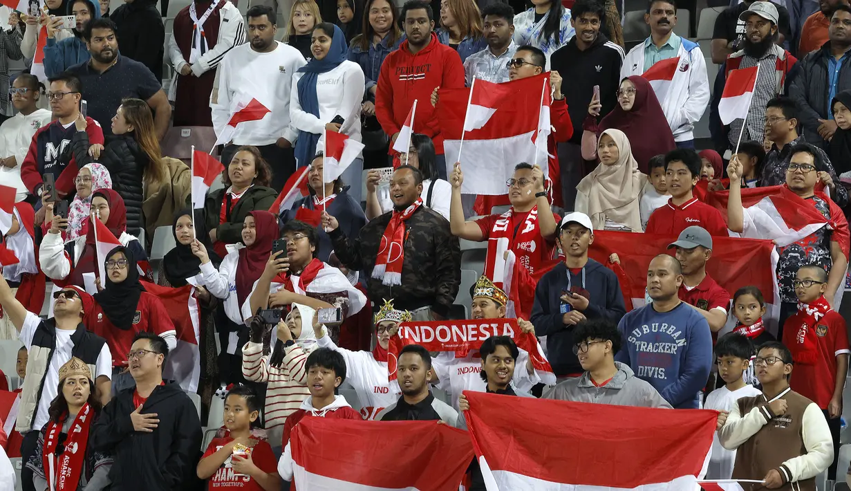 Para suporter Indonesia ikut menyanyikan lagu kebangsaan Indonesia Raya sebelum dimlainya laga kedua Grup D Piala Asia 2023 antara Timnas Indonesia menghadapi Vietnam di Abdullah Bin Khalifa Stadium, Doha, Qatar, Jumat (19/1/2024). (AFP/Karim Jaafar)