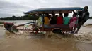 Warga Filipina mengunakan traktor menyebrangi banjir usai hujan lebat di Kota Candaba, Pampanga, Manila, Filipina (17/12). Sembilan orang tewas akibat bencana yang terjadi di Filipina. (REUTERS/Romeo Ranoco)