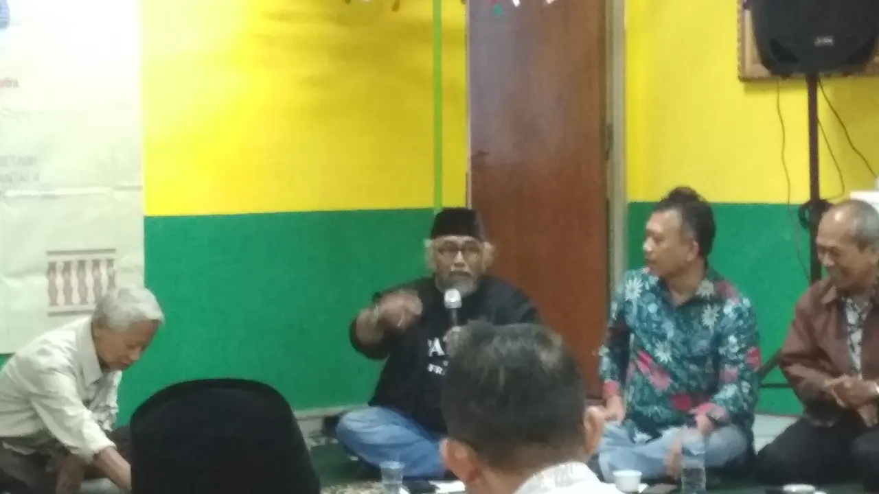 Iwan Aswan berbaju hitam dan berpeci hitam