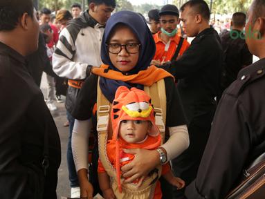 Orang tua dan bayi melewati pemeriksaan sebelum menonton laga Piala AFC 2018 antara Persija Jakarta vs Song Lam Nghe An di Stadion Utama GBK, Rabu (14/3/2018). Panpel menjual sekitar 65.000 lembar tiket. (Bola.com/Surya Bima Mahendarta)