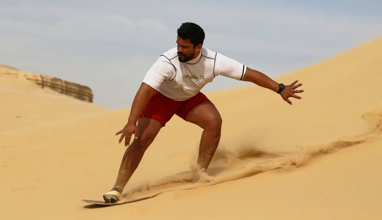Ekspresi sorang pria saat berseluncur menggunakan papan sandboards di gurun pasir Wadi el-Rayan Fayoum, Mesir (18/11). Peralatan yang dibutuhkan dalam olahraga ini yaitu sebuah papan luncur. (Reuters/Mohamed Abd El Ghany)