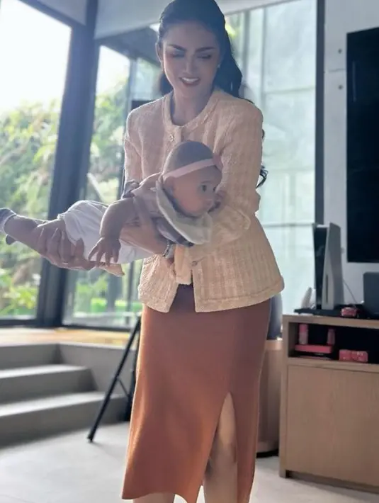 Krisdayanti mengenakan busana semi formal serba coklat dengan atasan blazer tweed berkancing. Dipadukan slit skirt warna sepadan.  [@krisdayantilemos]
