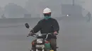 Pengendara motor mengenakan masker saat kabut asap tebal di Lahore (21/11/2019). Akibat kabut asap tebal penduduk Lahore mengeluh sakit tenggorokan, mata gatal dan penyakit lainnya.  (AFP Photo/Arif Ali)