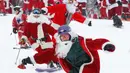 Pemain ski dan snowboarder berpakaian Santa Claus menuruni lereng gunung saat Santa Sunday ke-19 di Newry, Maine, AS, Minggu (2/12). Santa Sunday merupakan acara amal tahunan. (AP Photo/Robert F. Bukaty)
