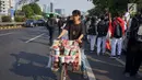 Seorang pedagang asongan berjualan di antara massa aksi di jalan tol dalam kota yang berada di depan Gedung DPR RI, Jakarta, Senin (30/9/2019). Adanya aksi unjuk rasa di sekitar lokasi dimanfaatkan para pedagang asongan untuk mencari rezeki. (Liputan6.com/Immanuel Antonius)