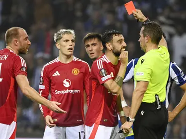 Pemain Manchester United, Bruno Fernandes, mendapat kartu merah setelah melakukan pelanggaran mengangkat kaki terlalu tinggi saat berduel dengan pemain FC Porto, Nehuen Perez, pada matchday 2 Liga Europa 2024/2025 di Estadio do Dragao, Jumat (4/10/2024). (AFP/Miguel Riopa)