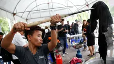 Seorang relawan sedang mewarnai pakaian agar menjadi hitam di Grand Palace di Bangkok, Thailand (17/10). Selama masa berkabung wafatnya raja Bhumibol Adulyadej warga Thailand mengenakan pakaian berwarna hitam.(Reuters/Edgar Su)