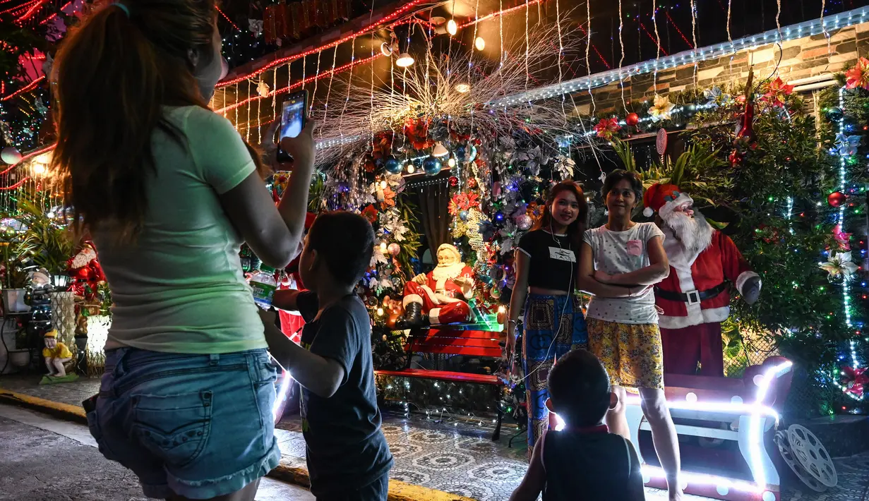 Orang-orang berfoto di depan sebuah rumah bertema Natal di Manila (21/12/2022). Perayaan Natal tinggal menghitung hari, warga Manila antusias mengunjungi rumah yang didekor dengan ornamen dan hiasan Natal itu. (AFP/Jam Sta Rosa)