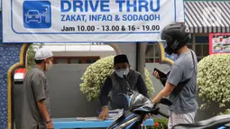 Petugas Amil Zakat melayani warga yang membayar zakat fitrah melalui sistem "drive thru" di Masjid Nurul Hidayah, Tanah Kusir, Jakarta, Selasa (19/5/2020). Layanan zakat "drive thru" selama pandemi COVID-19 ini diberlakukan dengan protokol kesehatan dan keselamatan. (Liputan6.com/ Johan Tallo)