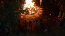 Warga melakukan ritual api unggun Holika di Ahmedabad, India, Minggu (12/3). Umat Hindu setempat menyalakan api unggun Holika pada malam sebelum festival Holi. (AFP PHOTO / SAM PANTHAKY)