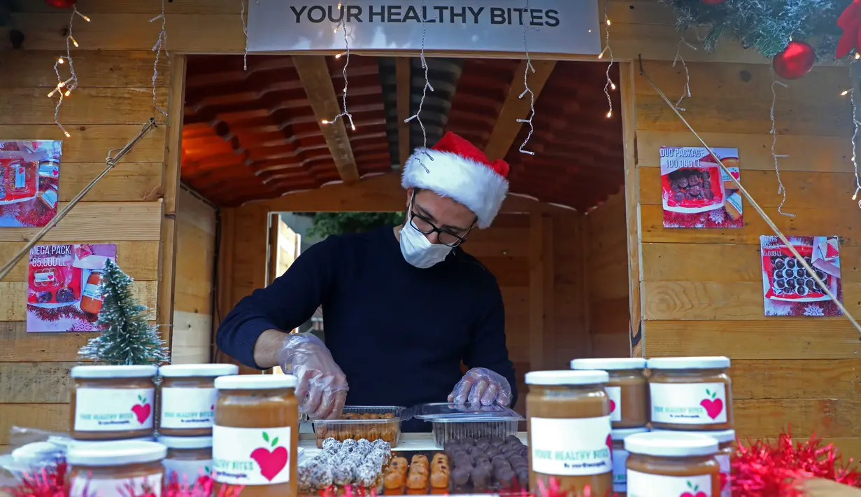 Seorang pedagang menata barang-barang di sebuah toko di kampung Natal di daerah Ashrafieh, Beirut, Lebanon, 6 Desember 2020. Sebuah kampung Natal dibuka pada Minggu (6/12) bagi para pedagang yang tokonya hancur akibat ledakan pelabuhan pada 4 Agustus lalu. (Xinhua/Bilal Jawich)