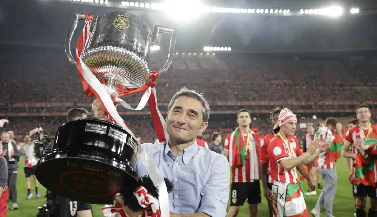 Pelatih Athletic Bilbao, Ernesto Valverde, mengangkat trofi setelah menjuarai Copa del Rey di Stadion Olimpico de Sevilla, Minggu (7/4/2024). Bilbao terakhir naik podium saat juara Copa del Rey 1984. Mereka sempat mencapai final enam kali, namun semuanya berakhir dengan kekalahan, termasuk pada musim 2020-2021. (AFP/Jaime Reina)