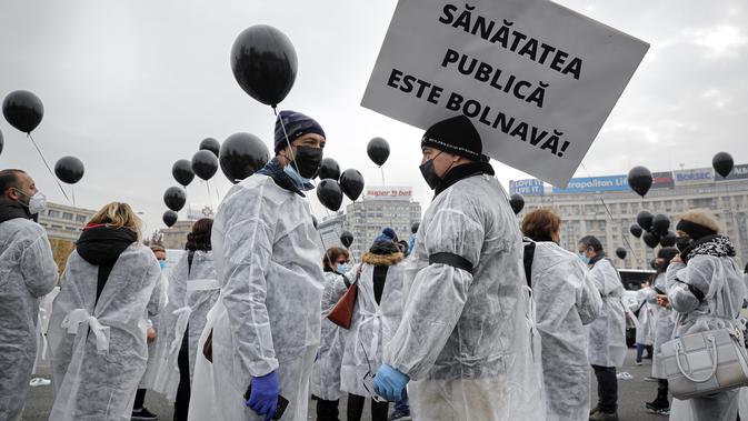 Para petugas medis yang mengenakan masker memegang balon hitam di Bucharest, Rumania, Selasa (17/11/2020). Aksi tersebut untuk mengenang pasien COVID-19 yang tewas dalam kebakaran di instalasi gawat darurat rumah sakit di Piatra Neamt, Rumania pada 14 November 2020 lalu. (AP Photo/Vadim Ghirda)