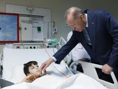 Gambar selebaran yang dirilis pada 22 Februari 2023 menunjukkan Presiden Turki Recep Tayyip Erdogan (kanan) mengunjungi korban gempa yang menerima perawatan di Fakultas Kedokteran Universitas Ankara setelah dipindahkan dari daerah yang dilanda gempa di Turki. Gempa berskala 7,7 magnitudo yang terjadi pada 6 Februari lalu itu merenggut ribuan nyawa dan hingga kini masih menjadi sorotan dunia. (Photo by Press Office of the Presidency of Turkey / AFP)