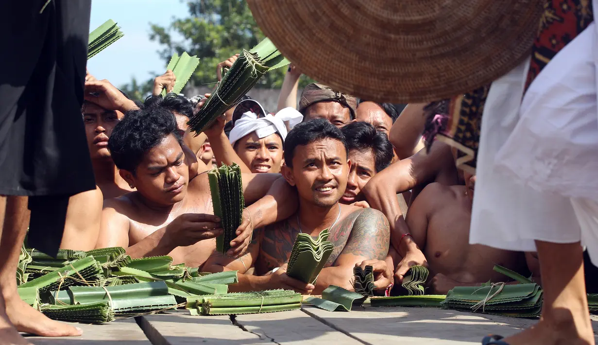 Sejumlah pria Bali menonton Perang Pandan di Bali (8/6). Perang Pandan merupakan salah satu tradisi yang dilakukan untuk menghormati dewa Indra atau Dewa perang. (AP/Firdia Lisnawati)