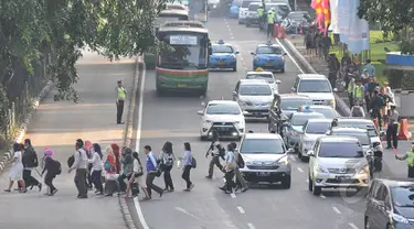 Sejumlah pekerja menyebrang jalan di kawasan Sudirman, Jakarta, Rabu, (22/4/2015). Adanya pengalihan arus untuk KAA membuat mereka terpaksa jalan kaki. (Liputan6.com/Johan Tallo)